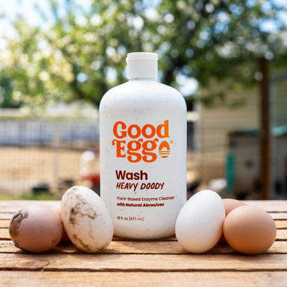 Heavy Doody wash on a wooden table with dirty eggs on the left side of the bottle and clean eggs on the right side. 